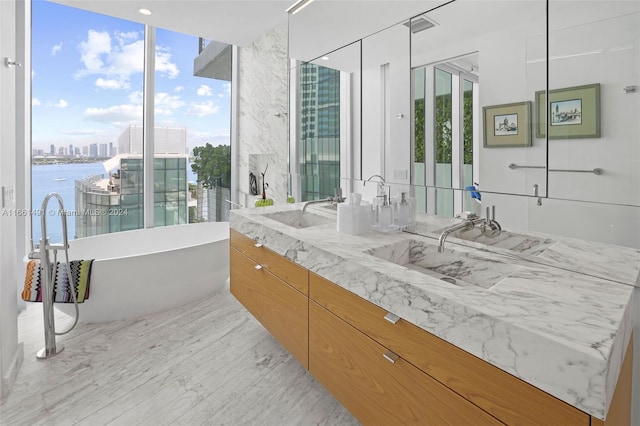 bathroom featuring a water view, a tub to relax in, hardwood / wood-style flooring, and vanity