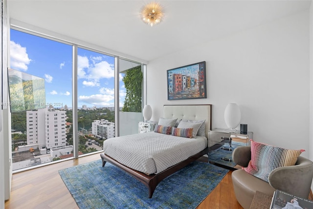 bedroom featuring access to outside, floor to ceiling windows, hardwood / wood-style floors, and multiple windows