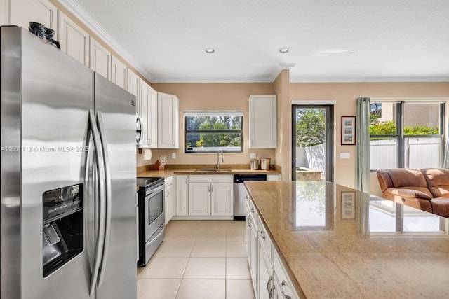 kitchen with appliances with stainless steel finishes, a sink, light stone counters, and white cabinetry