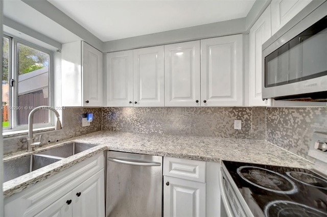 kitchen with sink, tasteful backsplash, white cabinetry, appliances with stainless steel finishes, and light stone countertops