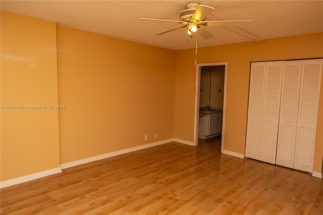 unfurnished bedroom featuring hardwood / wood-style flooring, ceiling fan, a textured ceiling, and a closet