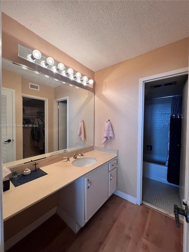 bathroom with hardwood / wood-style floors, vanity, a textured ceiling, and shower / bath combo with shower curtain