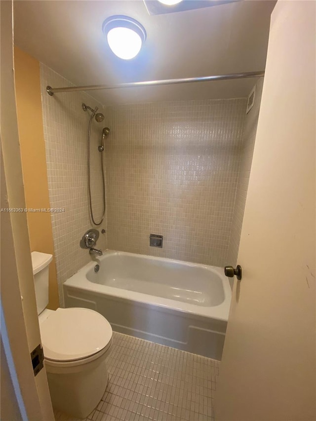 bathroom with tile patterned flooring, toilet, and tiled shower / bath