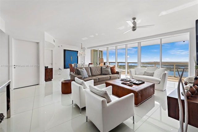 living room with ceiling fan with notable chandelier, a water view, and light tile patterned flooring