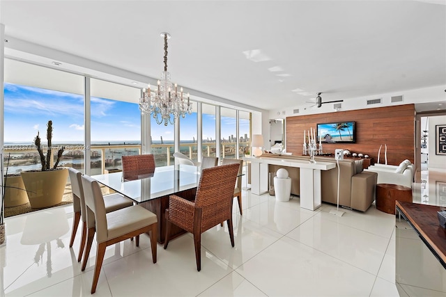 tiled dining area featuring ceiling fan with notable chandelier and a water view