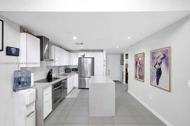 kitchen with wall chimney exhaust hood, a kitchen island, appliances with stainless steel finishes, light countertops, and a sink