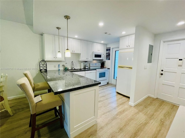 kitchen with white cabinets, kitchen peninsula, white appliances, and hanging light fixtures