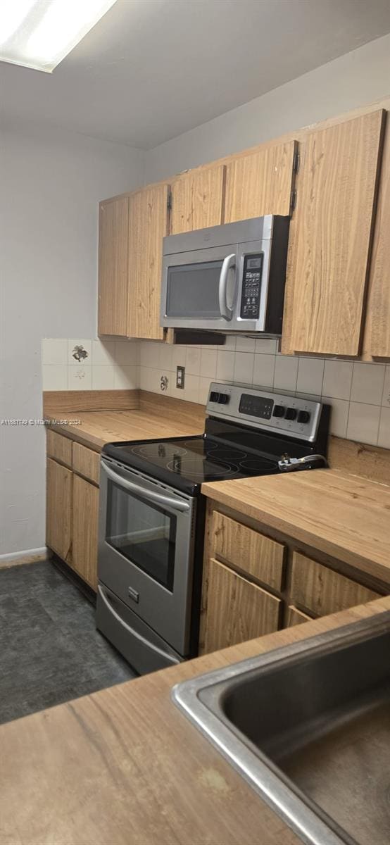 kitchen with decorative backsplash, appliances with stainless steel finishes, light brown cabinets, and sink