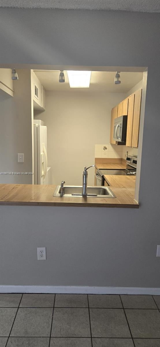 kitchen with dark tile patterned floors, stainless steel appliances, and sink