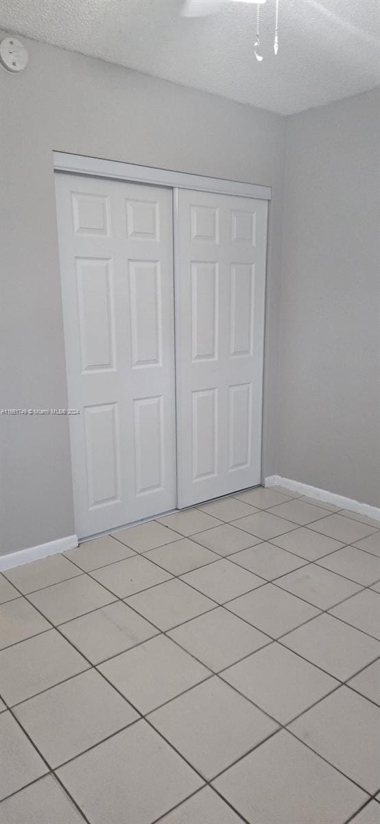 unfurnished bedroom featuring a textured ceiling, a closet, and light tile patterned flooring