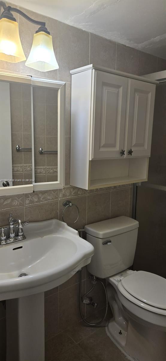 bathroom featuring decorative backsplash, tile patterned flooring, tile walls, and toilet