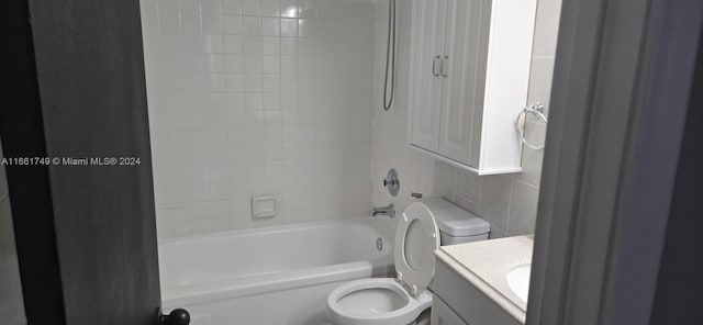 full bathroom with tiled shower / bath, vanity, tile walls, and toilet