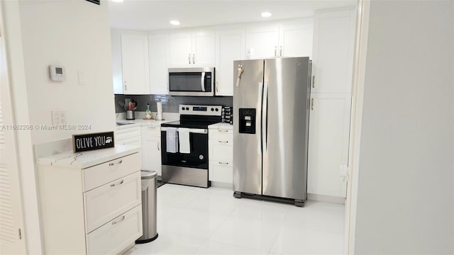 kitchen featuring decorative backsplash, light stone countertops, light tile patterned floors, appliances with stainless steel finishes, and white cabinetry