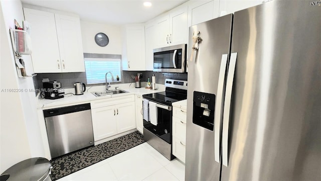 kitchen featuring decorative backsplash, stainless steel appliances, sink, light tile patterned floors, and white cabinets