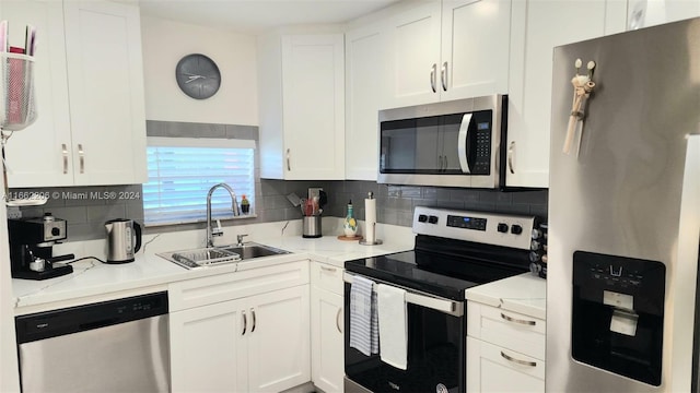 kitchen with white cabinetry, sink, light stone counters, decorative backsplash, and appliances with stainless steel finishes