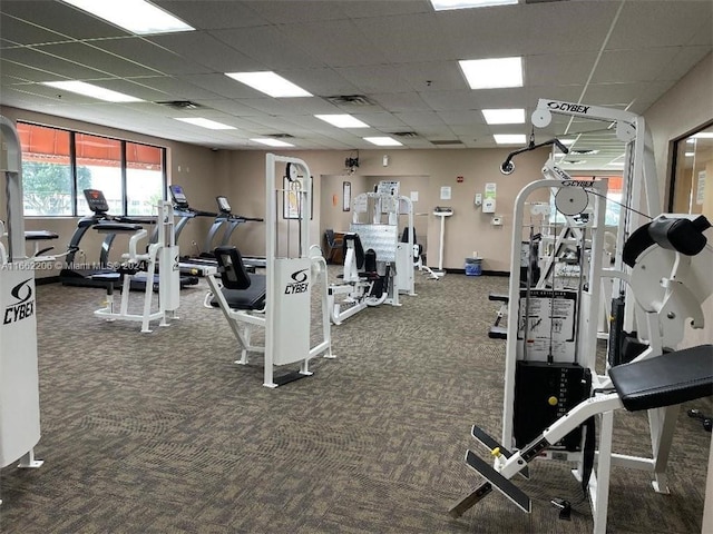 exercise room with dark colored carpet and a drop ceiling