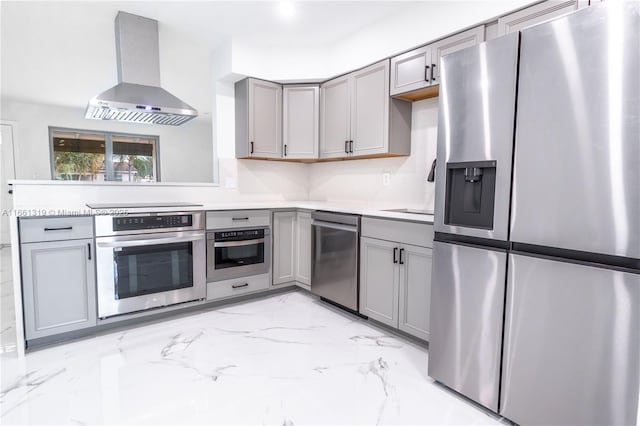 kitchen with marble finish floor, stainless steel appliances, wall chimney exhaust hood, and gray cabinets