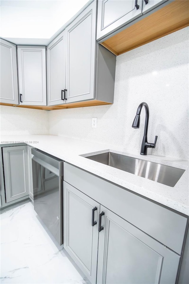 kitchen with gray cabinets, light stone countertops, sink, and dishwasher