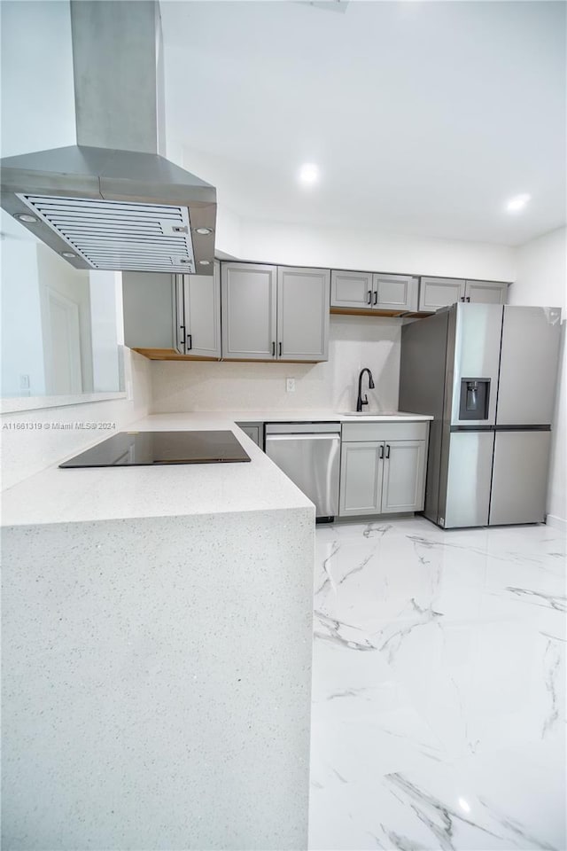 kitchen with sink, kitchen peninsula, gray cabinets, exhaust hood, and appliances with stainless steel finishes