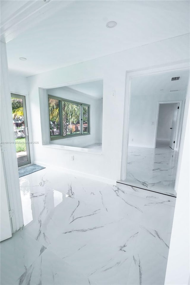 empty room featuring marble finish floor, plenty of natural light, and visible vents