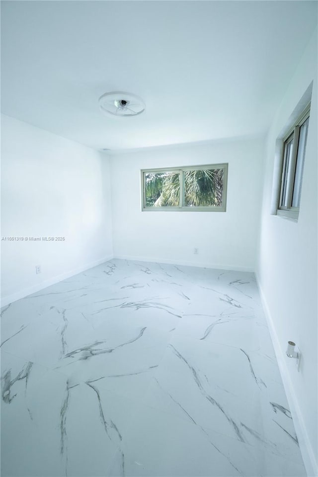 unfurnished room featuring marble finish floor and baseboards