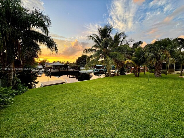 yard at dusk with a water view and a boat dock