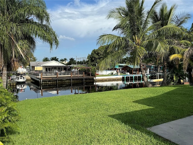 view of dock with a water view and a yard