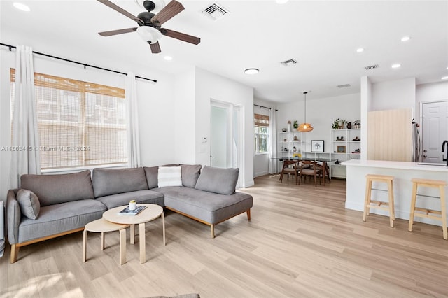 living room featuring light wood-type flooring, ceiling fan, and sink