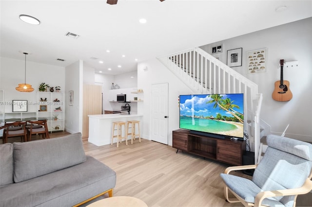 living room featuring ceiling fan and light hardwood / wood-style flooring