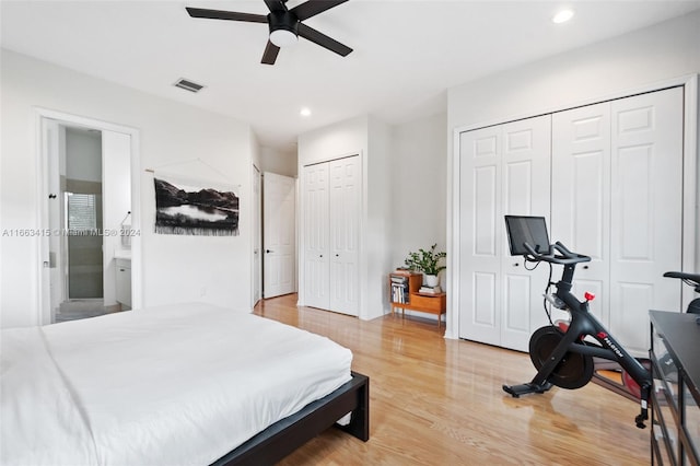 bedroom featuring light hardwood / wood-style flooring, connected bathroom, multiple closets, and ceiling fan