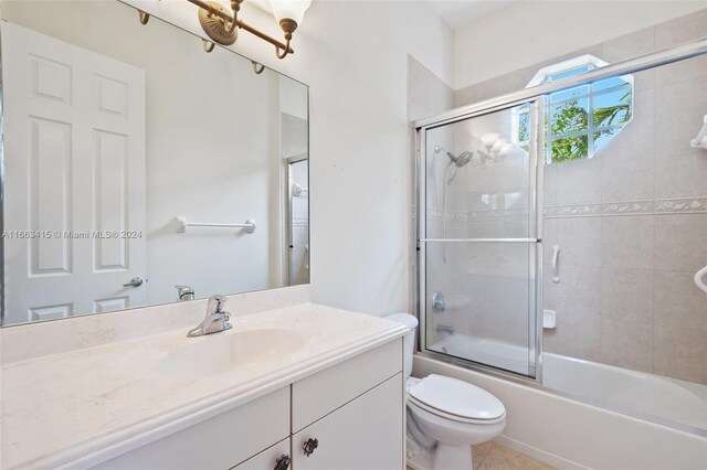 full bathroom featuring tile patterned floors, bath / shower combo with glass door, vanity, and toilet