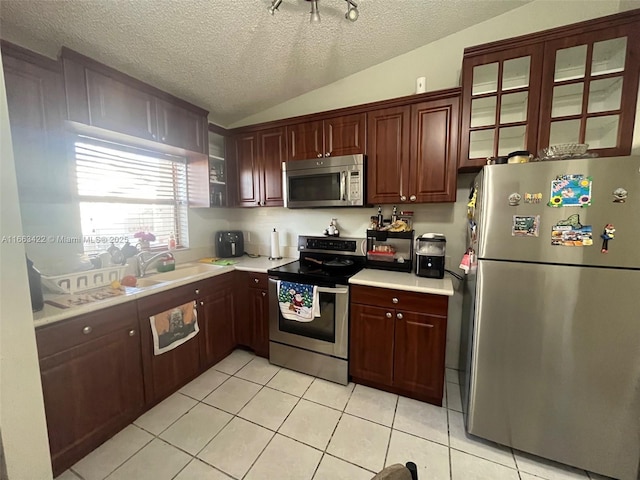 kitchen featuring light tile patterned floors, lofted ceiling, a sink, light countertops, and appliances with stainless steel finishes