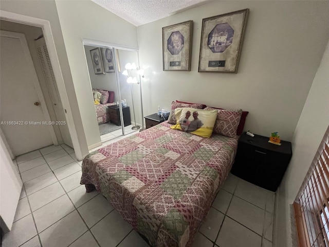 bedroom featuring light tile patterned floors, a closet, lofted ceiling, and a textured ceiling