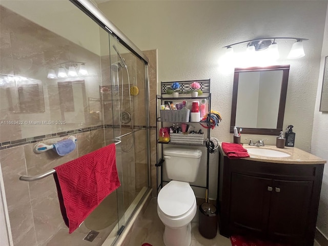 bathroom featuring toilet, a stall shower, vanity, and a textured wall