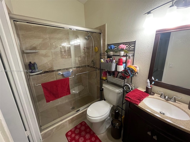 bathroom featuring a shower stall, toilet, vanity, and a textured wall