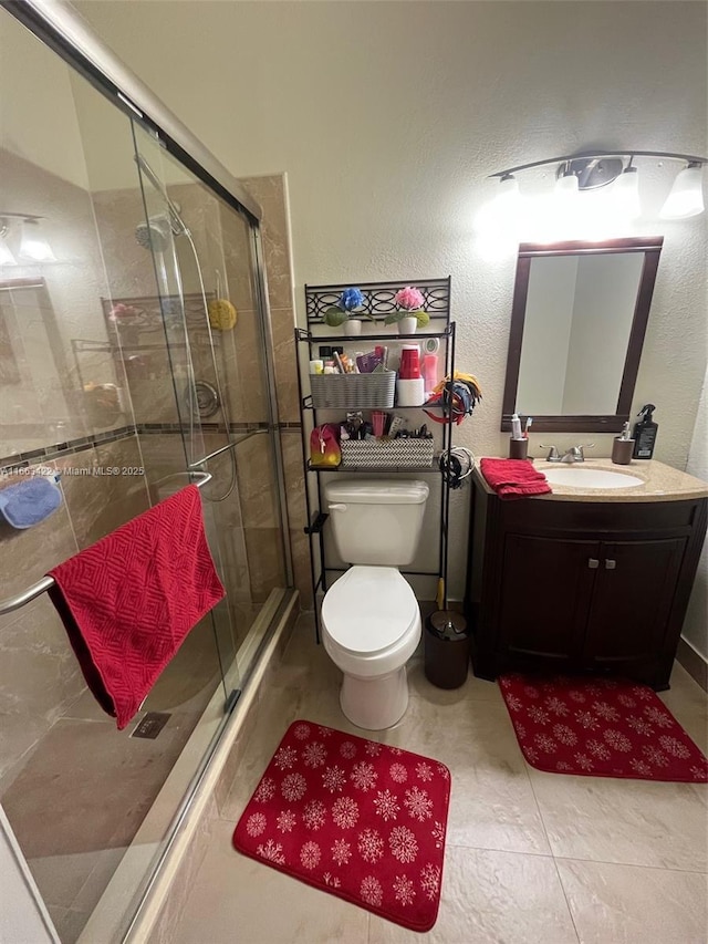 full bathroom featuring toilet, a stall shower, vanity, and a textured wall