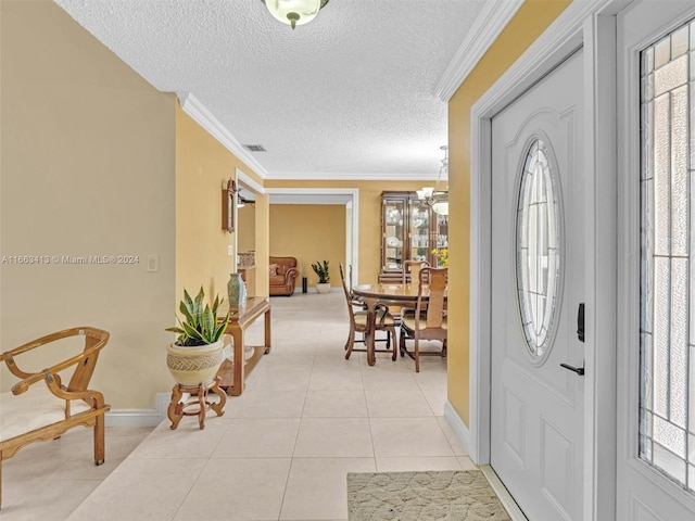 foyer entrance featuring a textured ceiling, ornamental molding, an inviting chandelier, and light tile patterned floors