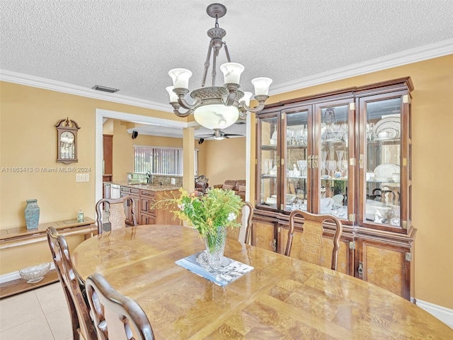 tiled dining area featuring a textured ceiling, ceiling fan with notable chandelier, and ornamental molding