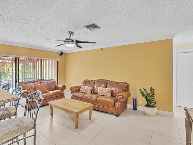 living room featuring ceiling fan, light tile patterned floors, a textured ceiling, and ornamental molding