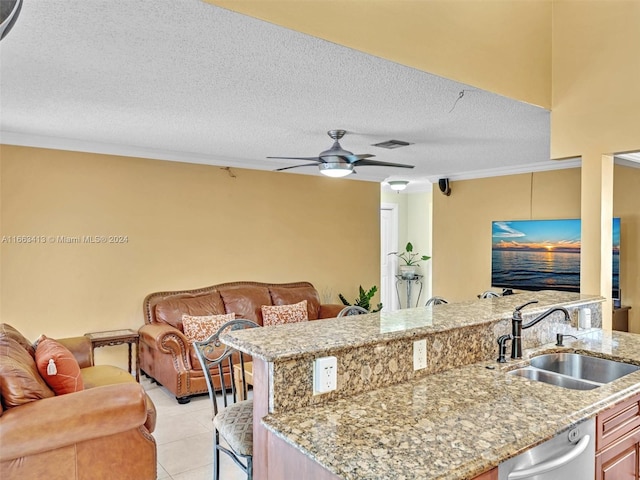 kitchen featuring a breakfast bar, a textured ceiling, sink, ceiling fan, and stainless steel dishwasher