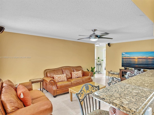 living room with a textured ceiling, light tile patterned floors, ornamental molding, and ceiling fan