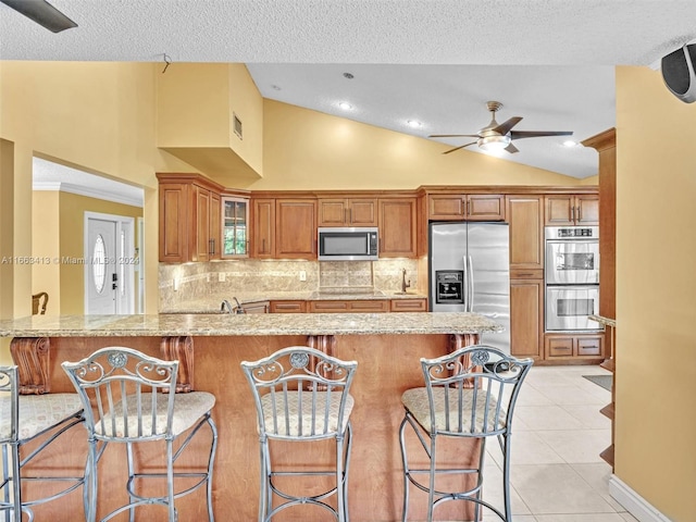 kitchen featuring kitchen peninsula, lofted ceiling, ceiling fan, and stainless steel appliances