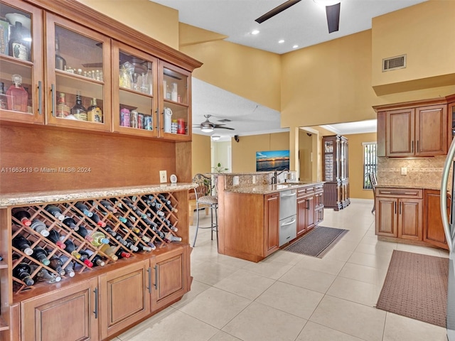 kitchen featuring light stone counters, ceiling fan, light tile patterned floors, and a breakfast bar area