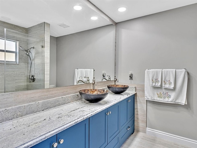 bathroom featuring tiled shower, vanity, toilet, and hardwood / wood-style flooring