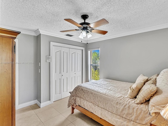 tiled bedroom featuring ceiling fan, a textured ceiling, a closet, and crown molding