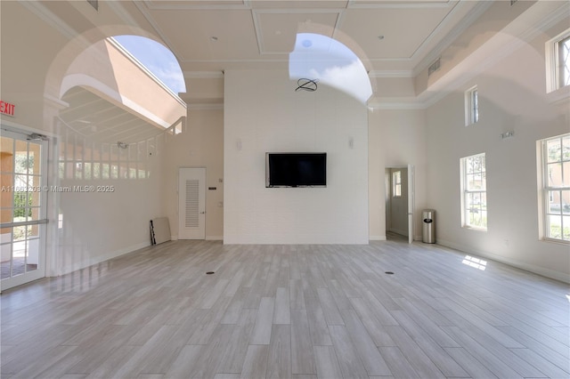 unfurnished living room with ornamental molding, light hardwood / wood-style floors, and a towering ceiling