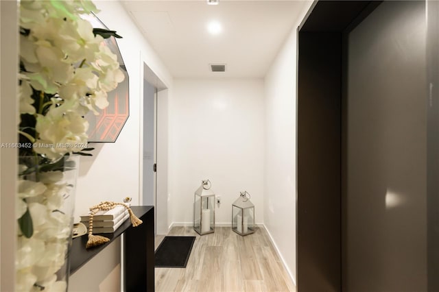 corridor featuring light wood-type flooring and elevator