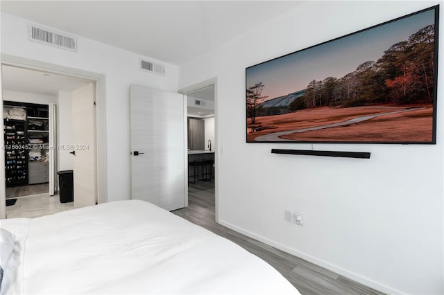 bedroom featuring ensuite bathroom and wood-type flooring