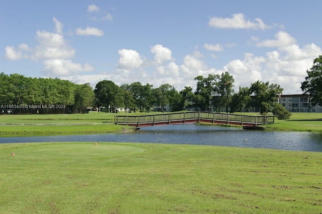 view of home's community with a water view and a lawn