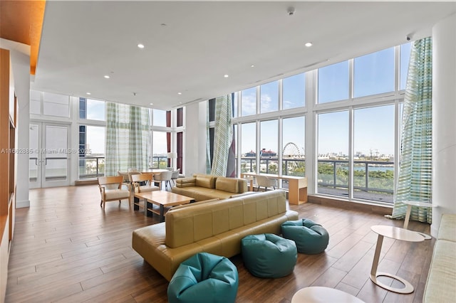 living area featuring a wall of windows, plenty of natural light, wood finished floors, and a city view